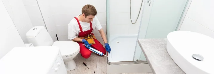 Person versiegelt Duschwanne mit Dichtmittel